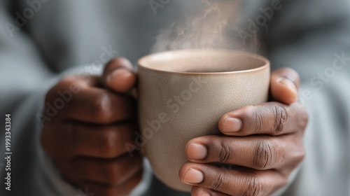 African american woman holding a hot steaming mug of coffee. Relaxing morning ritual with a warm beverage. Home comfort, cozy lifestyle and feeling of warmth during time of winter leisure.