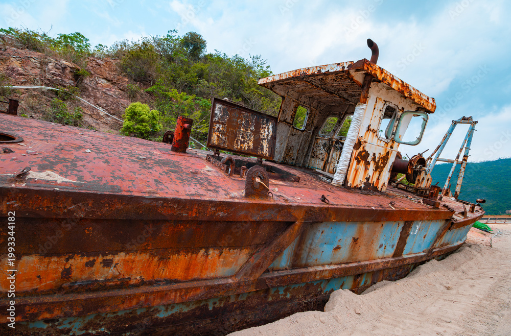 Fototapeta premium Rusted abandoned fishing boat stranded on sandy beach with decaying hull and corroded structure