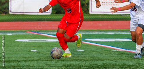Soccer Player Runs With Ball During Soccer Match on Field Turf