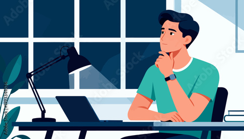 Young man sits pensively at desk under lamp glow