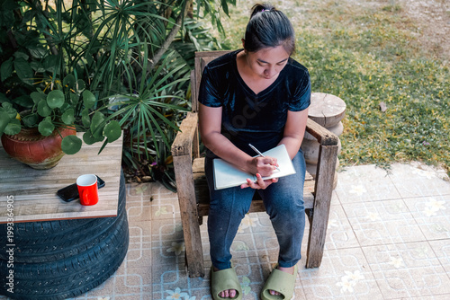 Young Asian Woman Writing in Notebook Outdoors, top view