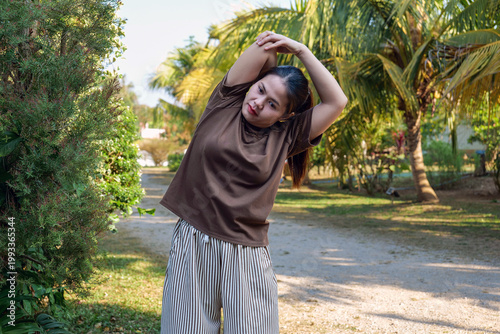 Young Asian Woman Stretching Body Sideways Outdoors in Garden Path
