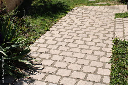 Schilderij op canvas Chemin en pavés, dallage carrés ancien beige clair dans le jardin devant la mais
