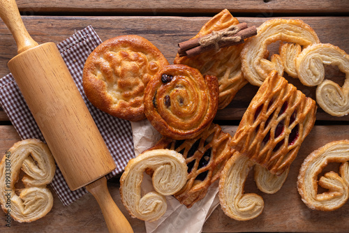 Freshly baked assorted pastries with a rolling pin on a rustic wooden table.
