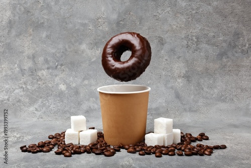 Coffee Cup Sits on a Surface Surrounded by Sugar and Coffee Beans With a Donu...