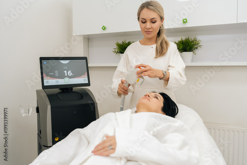 Fotografie Esthetician performing non invasive SMAS lifting photorejuvenation procedure on woman client neck, modern hardware cosmetology treatment for skin rejuvenation and facelift