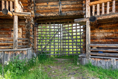 Tall wooden gates of a wooden fortress. Wooden walls made of round chopped logs of a reconstructed Old Slavic fortress. Bright sunny day.