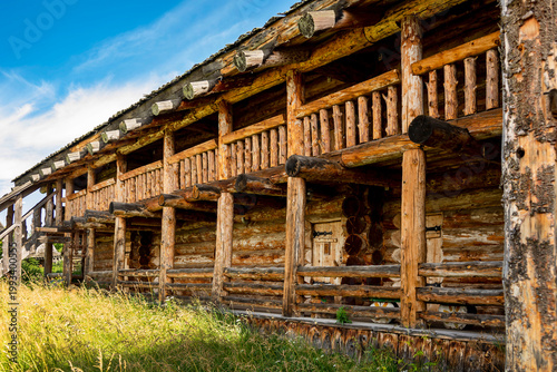 The impressive wooden walls of a reconstructed Old Slavic fortress, made of round, hewn logs. Old barracks and boyar chambers. A bright, sunny day.