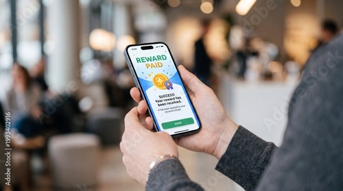 A person holding a smartphone displaying a rewards program interface in a modern café with soft lighting and blurred background
