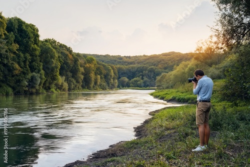 Person With Camera Stands by River During Morning Light Capturing Nature
