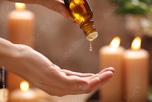 Hand Pouring Essential Oil Into Palm Near Candles in a Dimly Lit Room