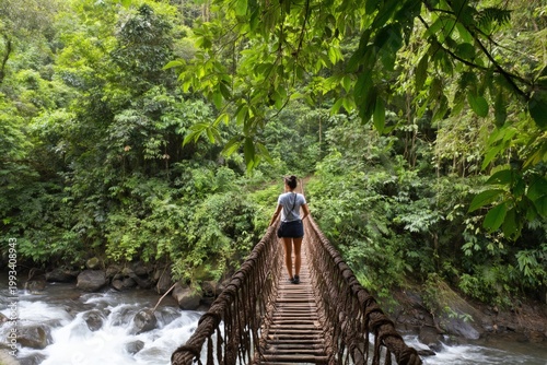 Woman Walks on a Rope Bridge in a Green Forest Near a River During the Daytime