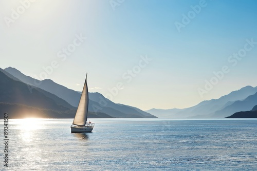 Sailboat Moves Across Water With Mountains in Background at Sunset in a Calm ...
