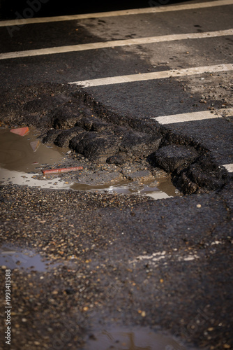 Urban scene with car passing by a big pothole in the asphalt