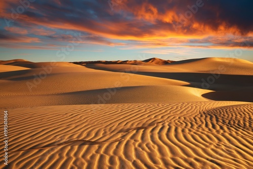 Sun Sets Over Sand Dunes at Desert Landscape With Colorful Clouds in Sky at E...