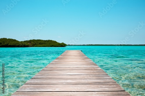 Wooden Dock Extends Over Blue Water Under Clear Sky at Tropical Location