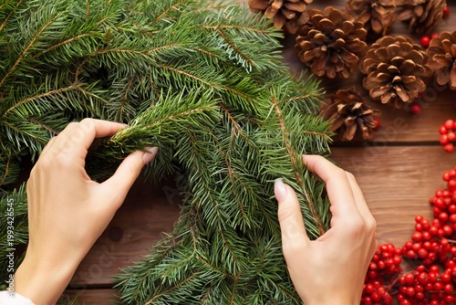 Hands Create a Holiday Wreath With Greens, Pine Cones, and Red Berries During...