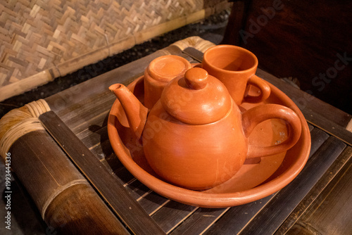 A brown traditional clay tea pot set on an old bamboo table