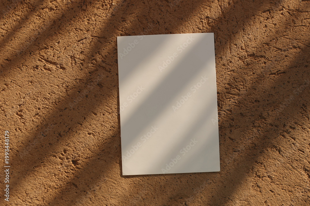 Naklejka premium Blank Summer Greeting Card invitation Mockup in Sunlight. Palm Leaves Shadow overlay. Ochre textured stone Background. Neutral Branding Template, Elegant Branding Wedding Stationery. Flatlay, top view