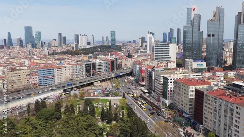 Istanbul cityscape showing bustling Zincirlikuyu intersection with heavy car traffic, large cemetery, modern Levent district skyline in background