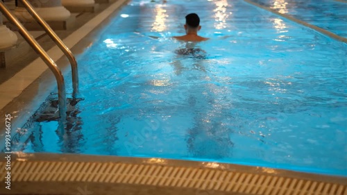 Young dark-haired man swimming in gym pool