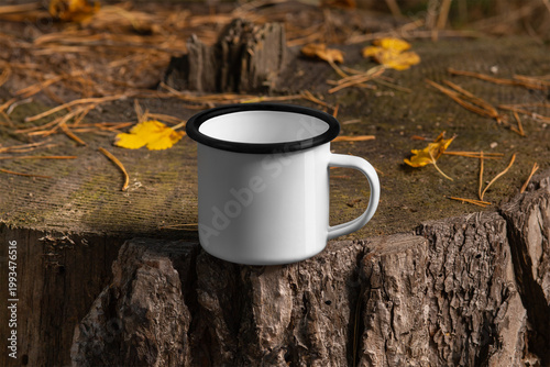 Mockup enamel white mug with a black rim on the trunk, product photo outdoors.