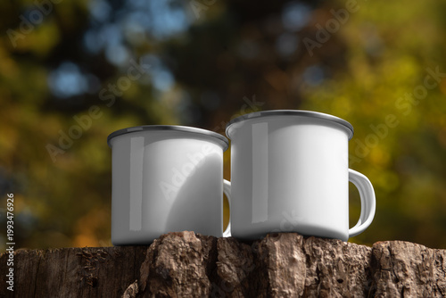 Mockup of enameled white mugs with iron rim, handle, set of steel dishes on wood log, on nature background, outdoors.