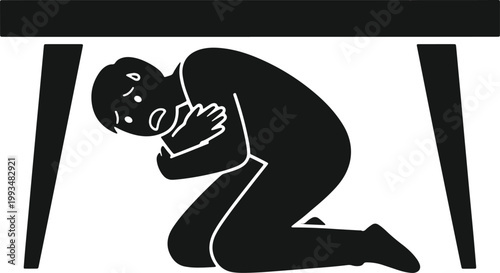 Person hiding under table during earthquake disaster safety drill.