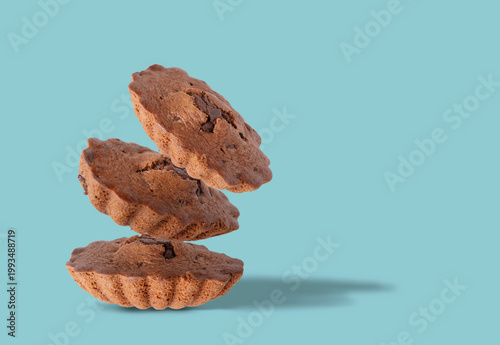 Three chocolate muffins flying on a blue background, space for text