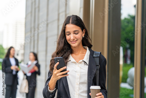 Three businesswomen talking and drinking coffee outdoors, showcasing teamwork, communication, and professional collaboration in a modern corporate environment. Ideal for business, leadership