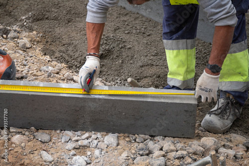 Foto Worker measuring concrete curb with yellow tape measure The Concept of accuracy