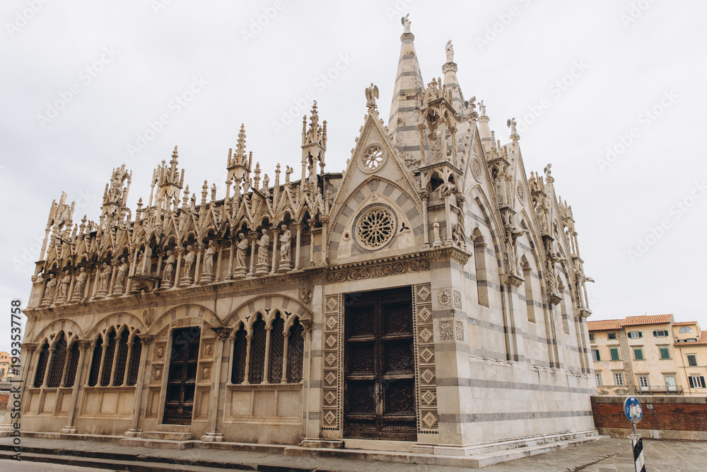 Fototapeta premium Gothic architecture of Santa Maria della Spina church with spires, statues, and intricate details along the Arno river in Pisa