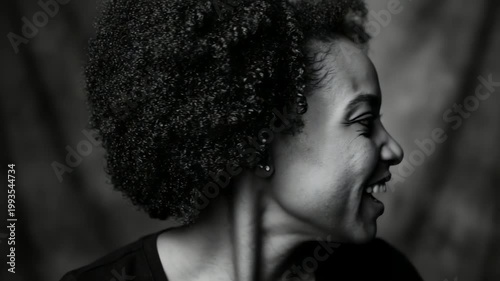 Profile portrait of a smiling woman with curly hair against a soft-focus background