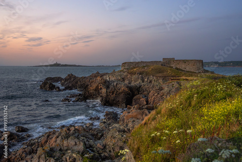 Scenic coastal landscape of Guernsey with lush greeney overlooking turquoise Atlantic ocean.