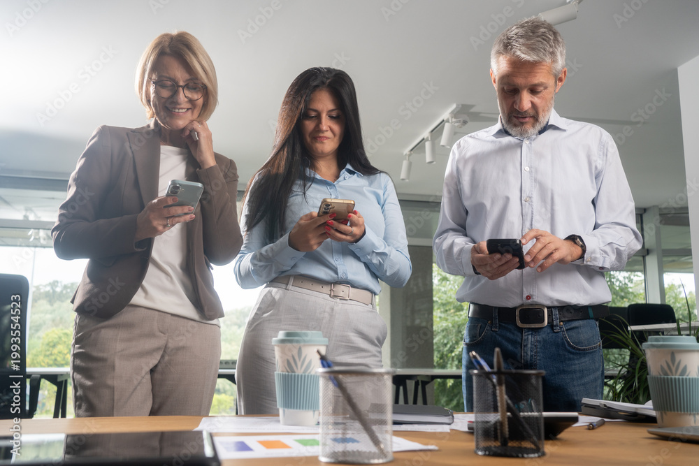 Obraz premium Business team taking a meeting break while using mobile phones