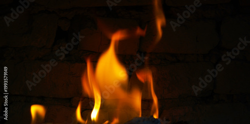 Bright orange fire flames dancing against a dark brick wall.