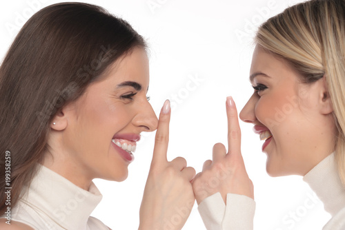 Tableau sur toile Studio shot of two young women side view portrait smiling and making playful shh