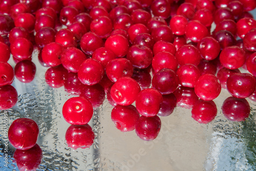 Ripe fresh cherries on a mirror glass with water drops close-up. Selective focus. Blurred background.