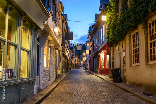 Traditional architecture and shops along an illuminated cobbled street at twilight in summer