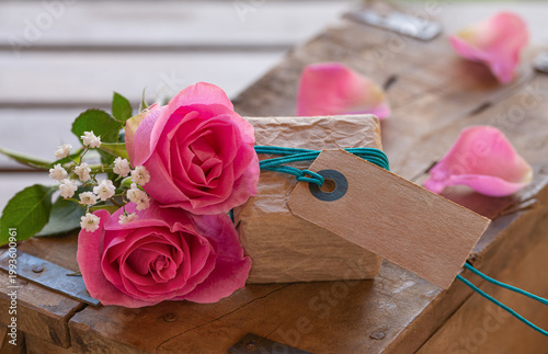 Cute little gift package with cardboard label, space for text and pink roses on old wood – Mother's Day – Birthday - Valentine's Day