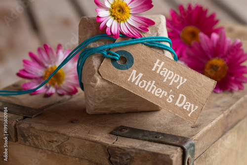 Mother's Day – Cute little gift package with cardboard label and text Happy Mother's Day on old wooden box