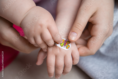 Hands of a child applying a band-aid to another child. Close-up view.
