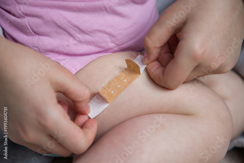 Hands of a child applying a band-aid to another child. Close-up view.