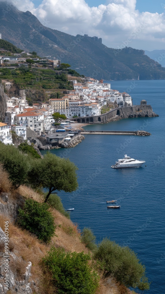 Obraz premium The scene shows a stone bridge leading to a cliffside town. Clear blue water and colorful buildings fill the view on a sunny day