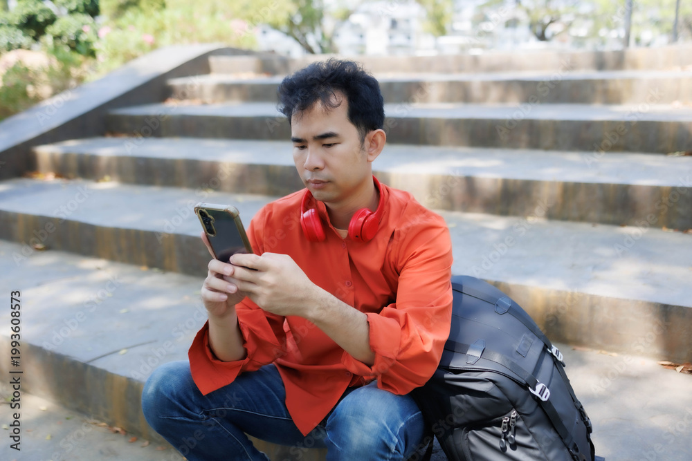 Obraz premium A man in an orange shirt sat on a bench at a coffee shop. He was relaxing, chatting, reading a book, and working—a perfect example of a relaxed lifestyle.