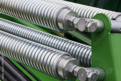 Silver spring made of steel. Part of big industrial or agricultural machine