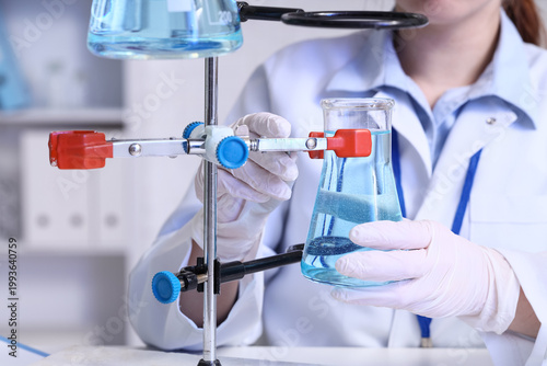 Female scientist with flask examining water quality in laboratory, closeup