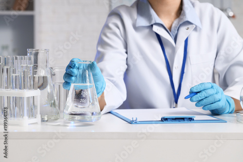 Female scientist with water samples at table in laboratory, closeup
