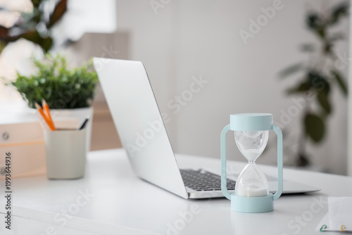 Hourglass with laptop on de...
