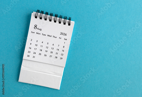 The desk calendar for August 2026 lies on a blue background.